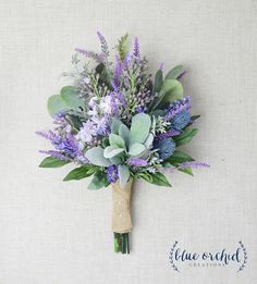 a boutonniere with purple flowers and greenery on a linen background that says blue orchid creations