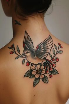 the back of a woman's neck with a bird and flowers tattoo on it