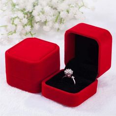 an open red velvet box with a ring in it