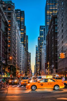 a city street filled with lots of traffic and tall buildings in the background at night