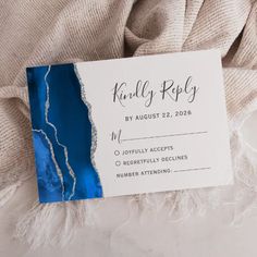 a white and blue wedding card on top of a blanket