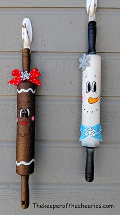 two toothbrush holders made to look like snowmen, one is wearing a dress