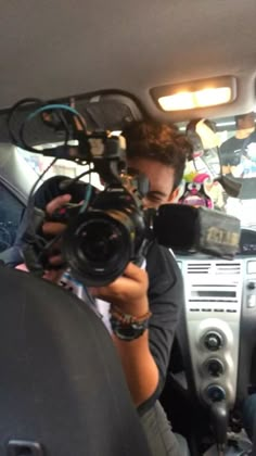 a man holding a camera in the back seat of a car