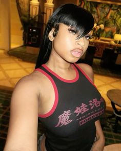 a woman with black hair wearing a red and black tank top in a hotel lobby