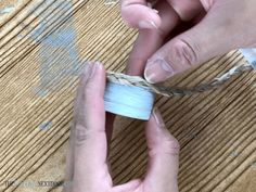 two hands are working on an object that is being made out of paper and twine