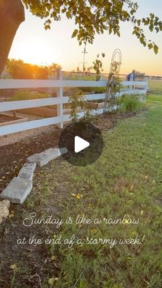 the sun is setting behind a white fence and some grass with steps leading up to it