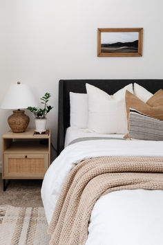 a bed with white sheets and pillows in a bedroom