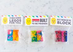 four bags of gummy bears are shown on the counter with stickers that say best friends, legos, and we were built for you