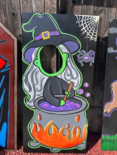 three painted wooden boards with witches and pumpkins on them in front of a fence