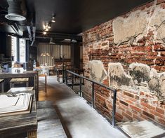 the interior of a restaurant with exposed brick and steel railings, along with tables and chairs