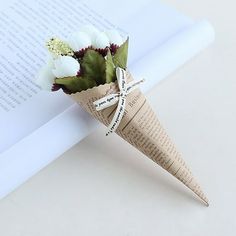 a paper cone with flowers on top of an open book