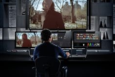 a man sitting at a desk in front of a computer monitor with multiple monitors on it