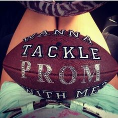 a person holding a football with the words tackle prom written on it's side