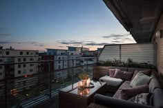 a balcony with couches, tables and candles lit up at night on the roof