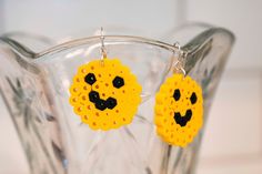 a pair of yellow earrings with black beading and a smiley face in the middle