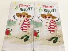 two white towels with snowmen on them, one has a merry and bright sign