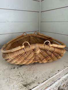 a wicker basket sitting on top of a wooden table next to a white wall