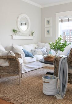 a living room with wicker furniture and white walls, including a round mirror on the wall