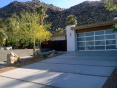 a modern house in the desert with palm trees and rocks on the front yard area