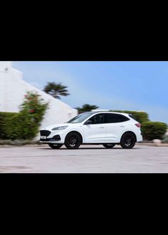 a white car parked in front of a house on the side of a road with black rims