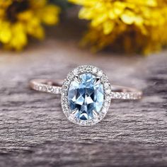 a blue and white diamond ring sitting on top of a wooden table next to yellow flowers