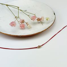 Delicate red thread bracelet with 4 gold beads in diamond pattern at center.