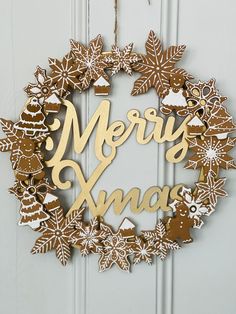 a christmas wreath hanging on the front door with merry xmas written in gold foil