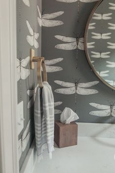 a bathroom with dragonflies on the wall next to a mirror and towel hanging from a hook