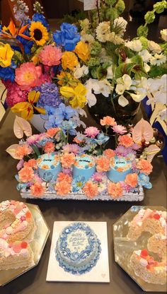 a table topped with cakes and flowers on top of it