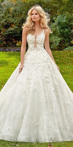 a woman in a wedding dress standing on the grass with her hands behind her back