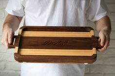 a man holding a wooden cutting board with the word dolce engraved on it in cursive writing