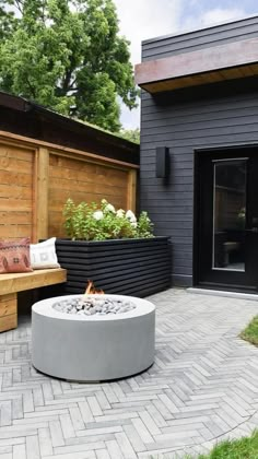 a fire pit sitting on top of a brick patio next to a wooden fence and building