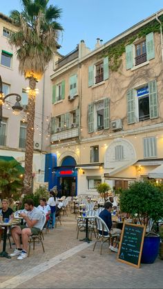 people sitting at tables in front of buildings