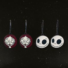 three keychains with faces on them sitting next to each other in front of a black background