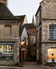 people walking down an alleyway between two buildings with shops on each side and in the middle