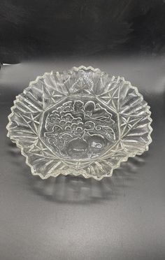 a clear glass bowl sitting on top of a metal tablecloth covered surface with an ornate design