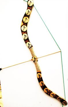 an animal print bow and arrow on a white surface with green string attached to it