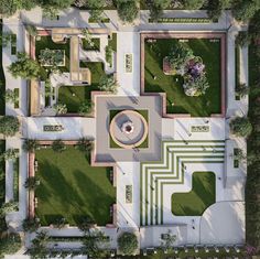 an aerial view of a park with a fountain and trees in the center, surrounded by greenery