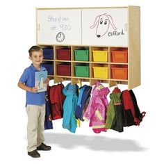 a young boy standing in front of a coat rack