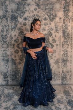 Spice up your style statement with this navy blue coloured lehenga No matter if you want to be a showstopper at any wedding or small ceremony, then this blue coloured lehenga is apt for you. This lehenga is decorated with sequined work and comes along with an off-shoulder velvet blouse. This lehenga is easy to carry so that you can dance around with ease and feel relaxed throughout the ceremony. Due to its appealing design, this lehenga will prove to be a great choice for you without burning a h Navy Blue Velvet Blouse, Blue Sequin Lehenga, Lehenga Blouse Styles, Dark Blue Lehenga, Trendy Lehenga Designs, Velvet Skirt Outfit, Blue Velvet Blouse, Velvet Blouse Design, Bride Lehenga