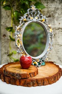 an apple sitting on top of a piece of wood with a mirror in the background