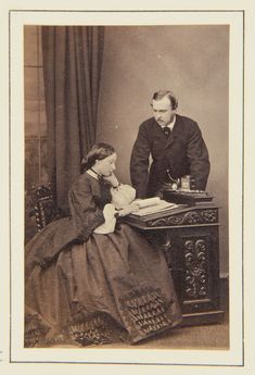 an old photo of a man and woman sitting at a desk in front of a book