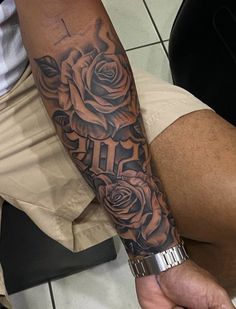 a man with a cross and roses tattoo on his arm