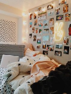 an unmade bed with many pictures on the wall and lights hanging above it in a bedroom