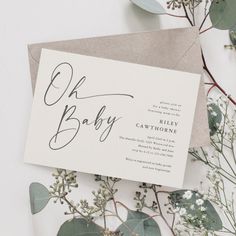 an envelope with the word oh baby written on it next to some flowers and greenery