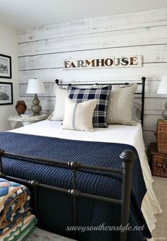 a bed with blue and white pillows in a bedroom next to pictures on the wall