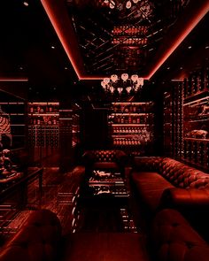 a dimly lit wine cellar with leather couches and chandeliers in the ceiling