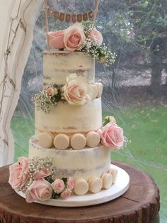 a three tiered wedding cake with pink flowers on the top and white icing