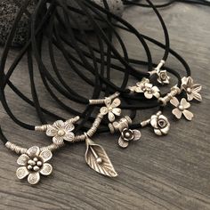 Unique one of a kind silver flower charms choker. 10 different necklaces, made with a long black leather cord and 10 unique silver flower pendants with silver beads. This necklaces can be adjusted to chokers or can be long necklaces like you can see in the picture. Perfect stacking necklaces that will rock your outfit and will be easy to match other accessories. You can see in 2 of the pictures that each flower choker has a number, that way you know which one are choosing. A unique addition to y Adjustable Metal Necklace With Flower Charm, Flower Pendant Necklace With Adjustable Cord, Adjustable Flower Necklace Nickel Free, Handmade Adjustable Charm Necklace, Adjustable Nickel-free Necklace With Flower Pendant, Festival Jewelry With Flower Charm, Nickel-free Adjustable Flower Pendant Necklace, Unique Silver Necklace With Adjustable Cord, Adjustable Flower Pendant Necklaces With Cord