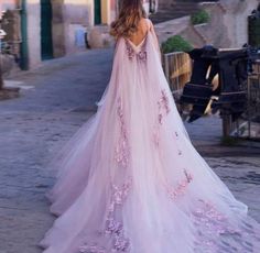 a woman in a pink wedding dress walking down the street with her back to the camera